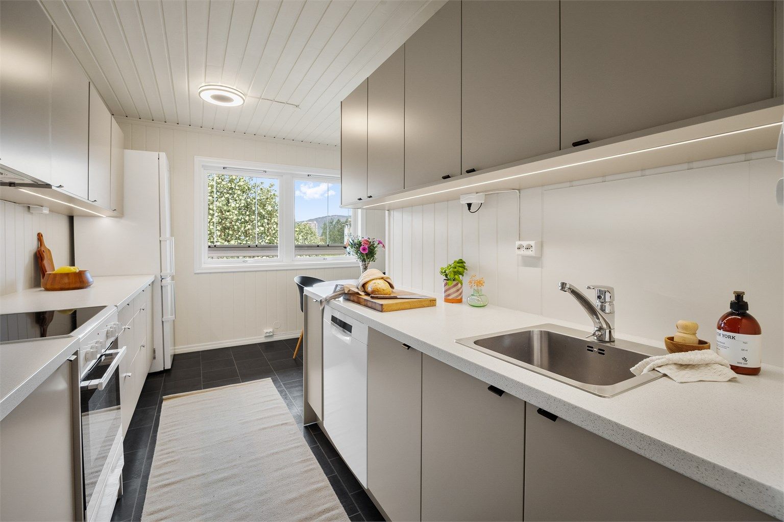 Kjøkken med innredning med glatte fronter og benkeplate med laminert overflate med nedfelt kjøkkenvask.