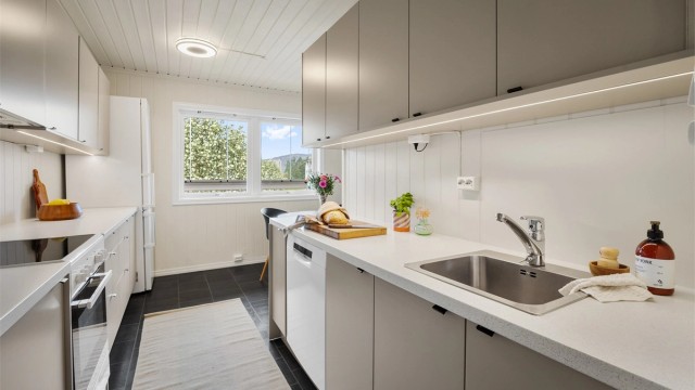 Kjøkken med innredning med glatte fronter og benkeplate med laminert overflate med nedfelt kjøkkenvask.