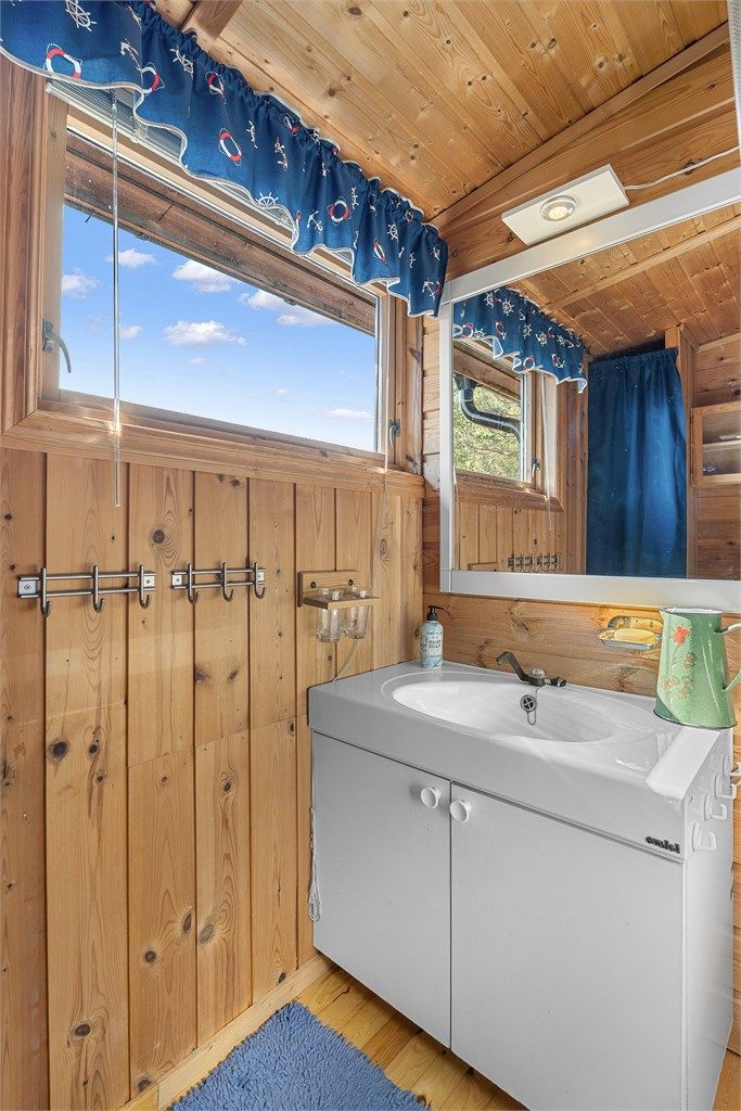 Praktisk bad på 3 kvm med servantinnredning og speil samt dusjkabinett. Hytta har solcellepanel og vannforsyning tilkoblet pumpe fra regnvann.