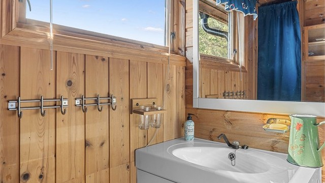 Praktisk bad på 3 kvm med servantinnredning og speil samt dusjkabinett. Hytta har solcellepanel og vannforsyning tilkoblet pumpe fra regnvann.