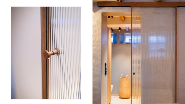 En elegant skyvedør i glass og tre fører inn til badet.