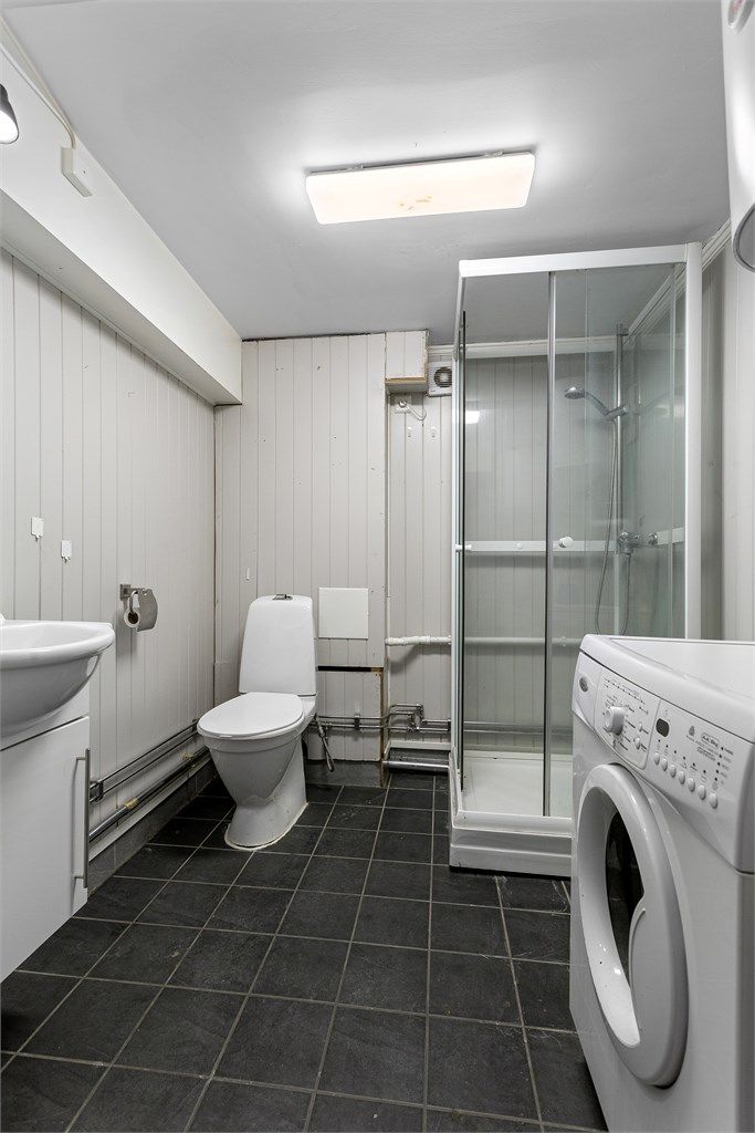 Badet i underetasjen har flislagt gulv med gulvvarme, dusjkabinett og opplegg for vaskemaskin