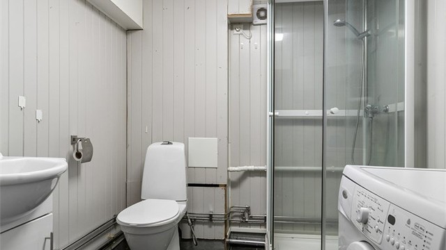 Badet i underetasjen har flislagt gulv med gulvvarme, dusjkabinett og opplegg for vaskemaskin