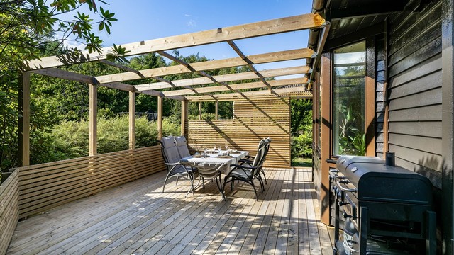 På den store terrassen er det god plass til grilling og sammenkomster utendørs. Spilevegger og hagens beplantning ivaretar privatlivet.