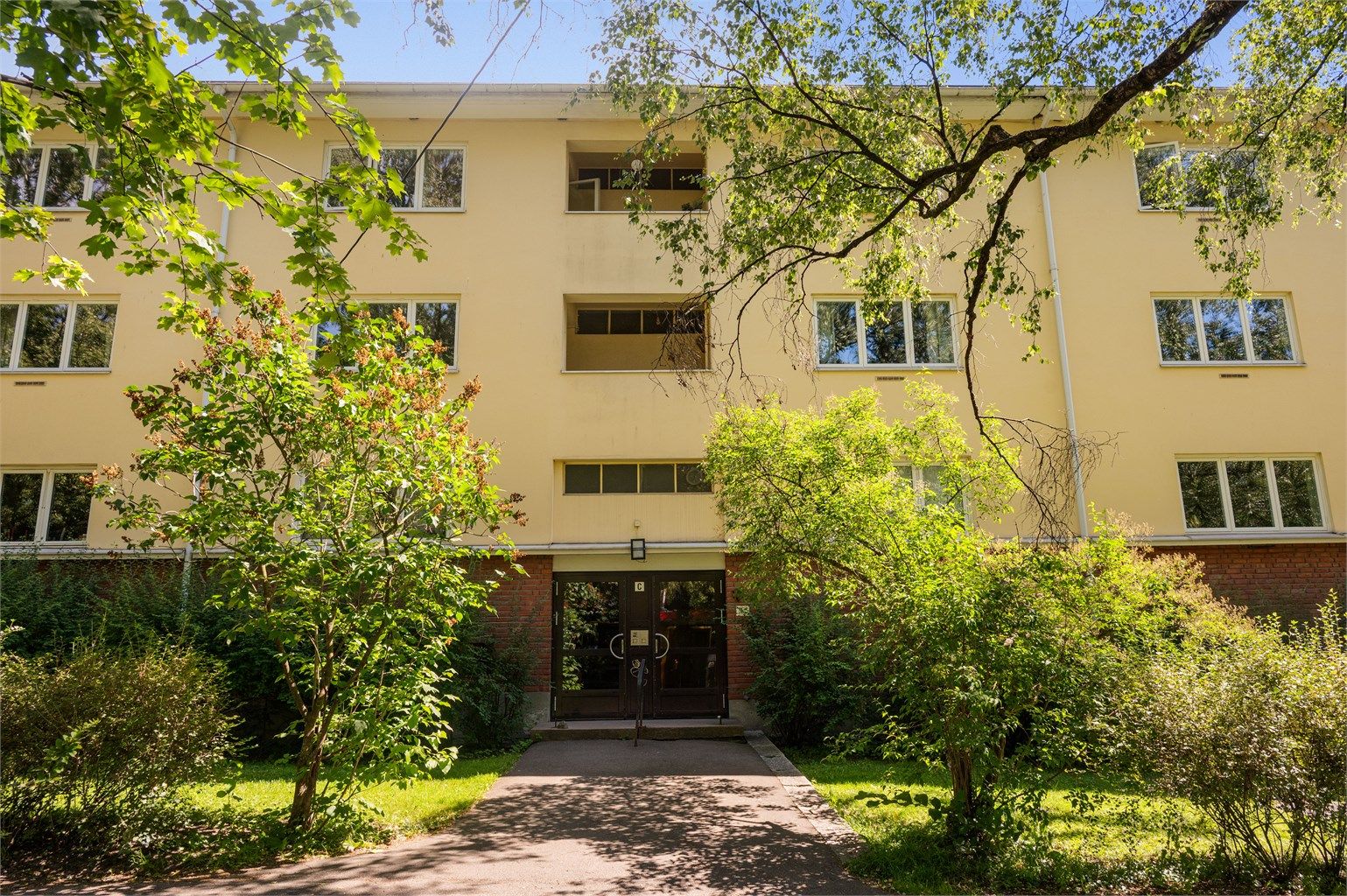 Leilighetens fasade, pent opparbeidet og hyggelig uteområde. 