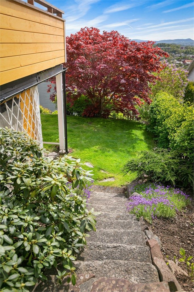 Eiendommen har en pent opparbeidet hage med plen, beplantning og steintrapper.