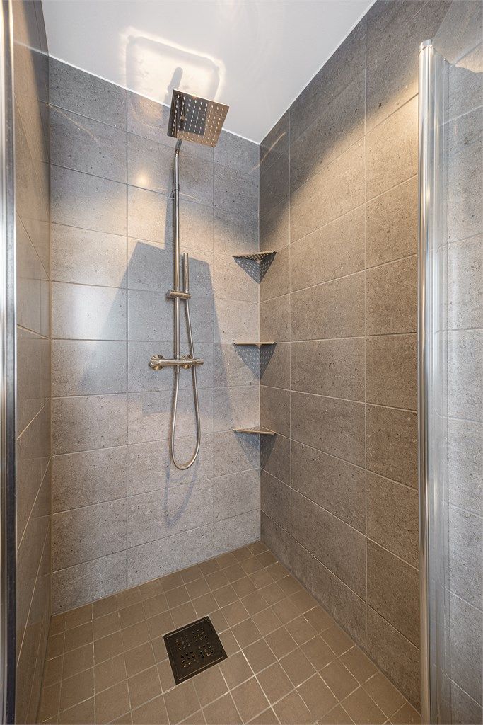 Den romslige dusjnisjen er utstyrt med en regnfallsdusj for ekstra komfort.