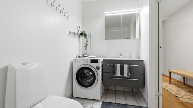 Leilighetens bad/wc har varmekabler i gulvet for lun varme, det er montert en moderne baderomsinnredning med hvit servanttopp og fint speilskap med lys over