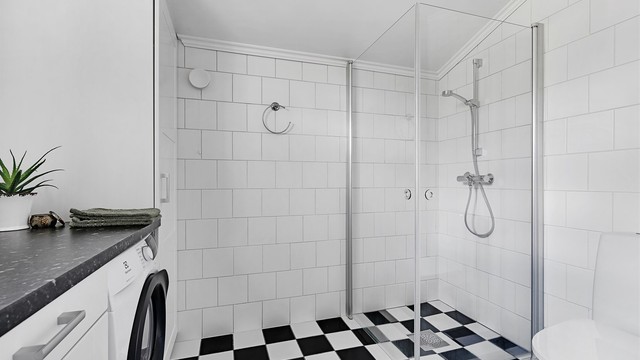 Rommet inneholder toalett, dusjvegger, samt opplegg for både vaskemaskin og tørketrommel i innredningen. Her det praktisk arbeidsbenk og nedfelt vaskekum.