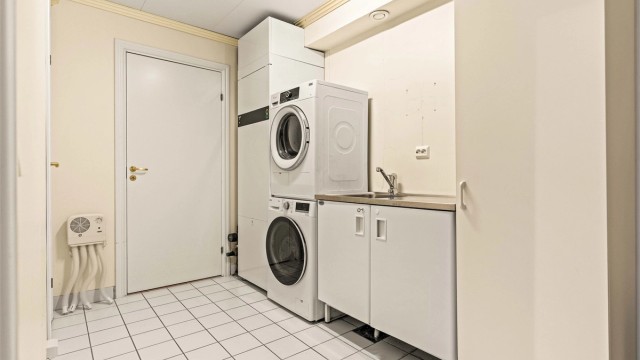 Praktisk vaskerom med flislagt gulv med gulvvarme og opplegg for vaskemaskin. Her er også boligens avtrekksvarmepumpe.
