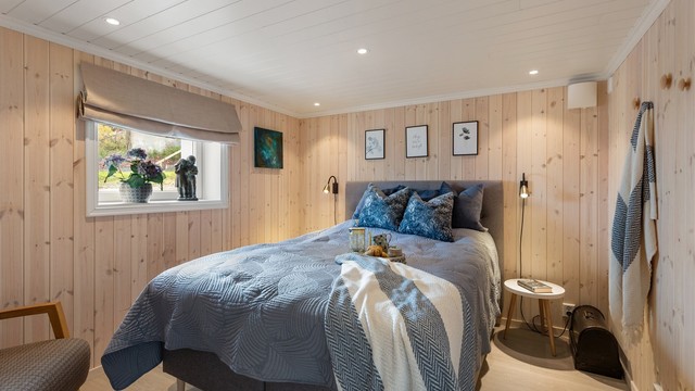 Et av soverommene i underetasjen, med lyst panel på veggene som skaper en varm atmosfære. Ikke godkjent for varig opphold.