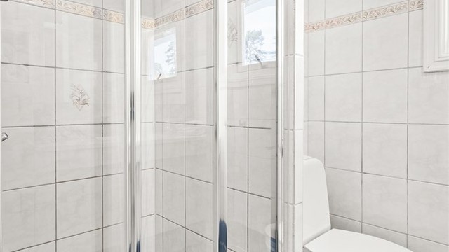 Dusjnisje med glassvegg og glassdør.