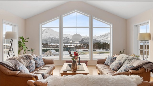 De store, spesialtilpassede vinduene rammer inn en storslått utsikt mot fjellheimen.