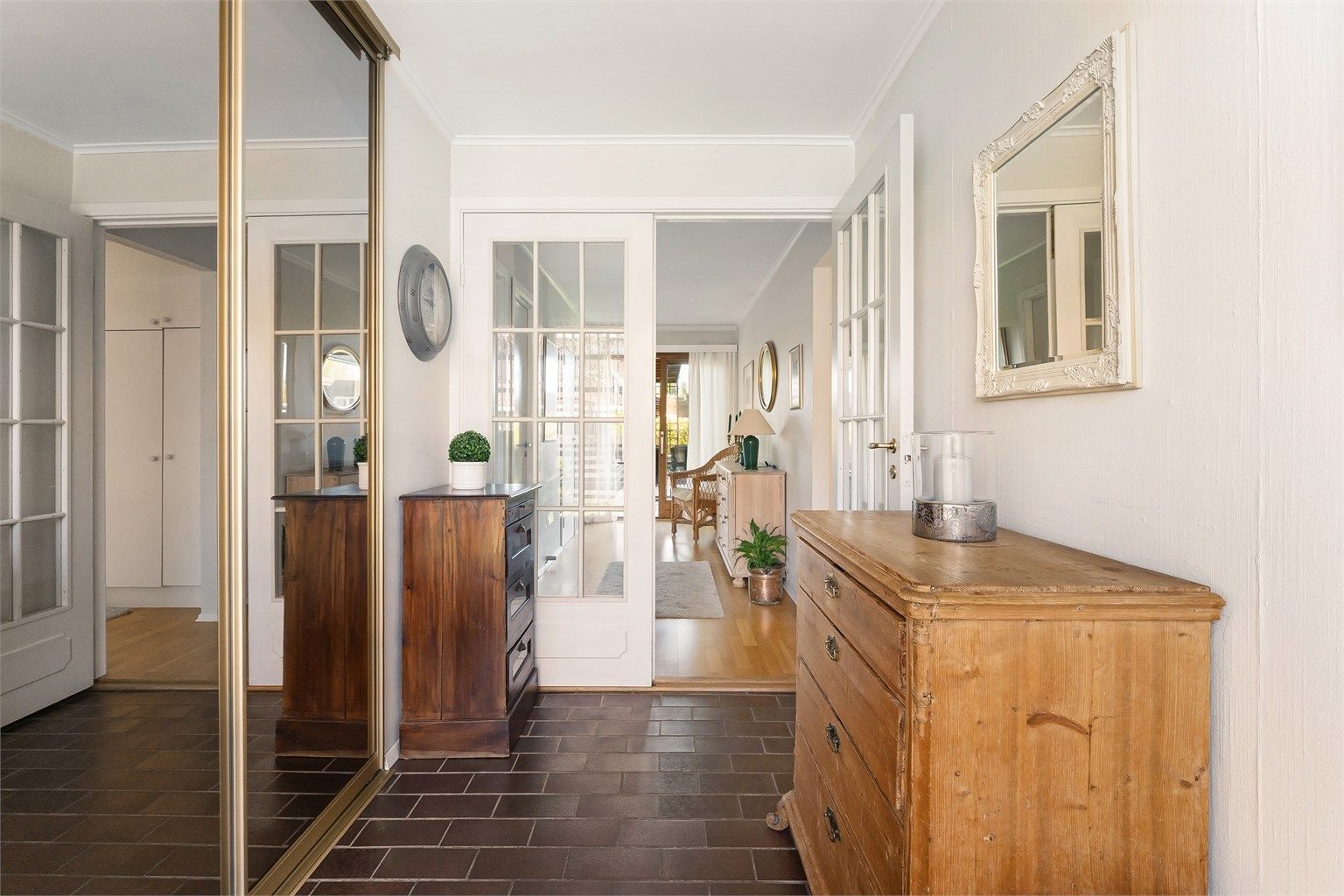 Fra yttergangen åpner boligen seg opp med doble glassdører inn mot stuen. Stor skyvedørsgarderobe med speil gir god plass til oppbevaring av sko og yttertøy.