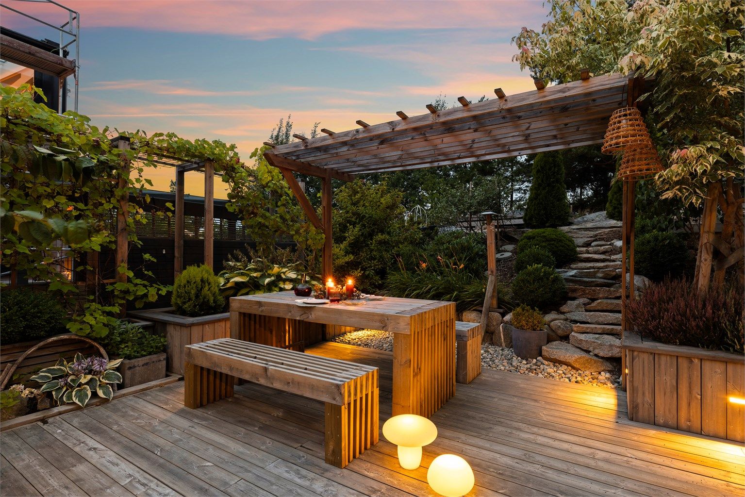 Frodige prydbusker, planter og naturstein gir glidende overgang fra hagen til skogsterrenget ovenfor.