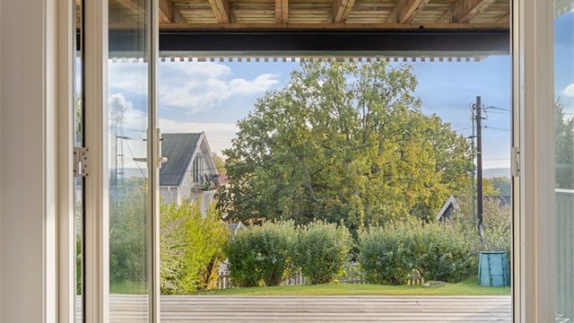 Terrassedør fra 2022 åpner opp fra tv-stuen mot den overbygde uteplassen.