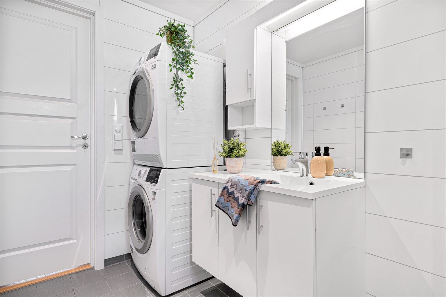 Vegghengt servant med tilhørende overskap og speil med belysning. Ellers god plass til både vaskemaskin og tørketrommel. 