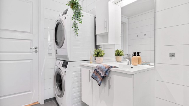 Vegghengt servant med tilhørende overskap og speil med belysning. Ellers god plass til både vaskemaskin og tørketrommel.