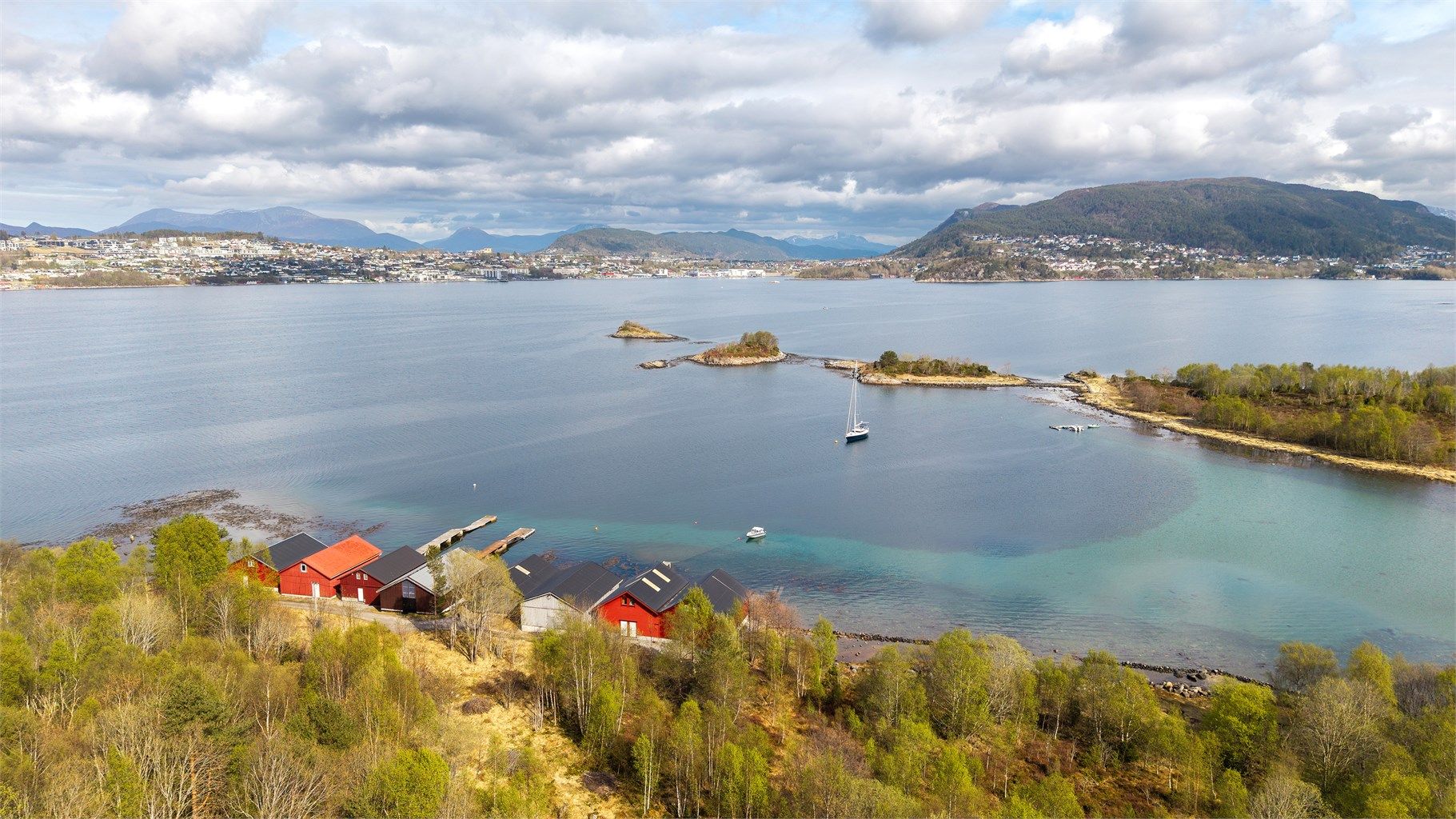 Et vakkert kystlandskap med holmer, skjær og fjell i horisonten.