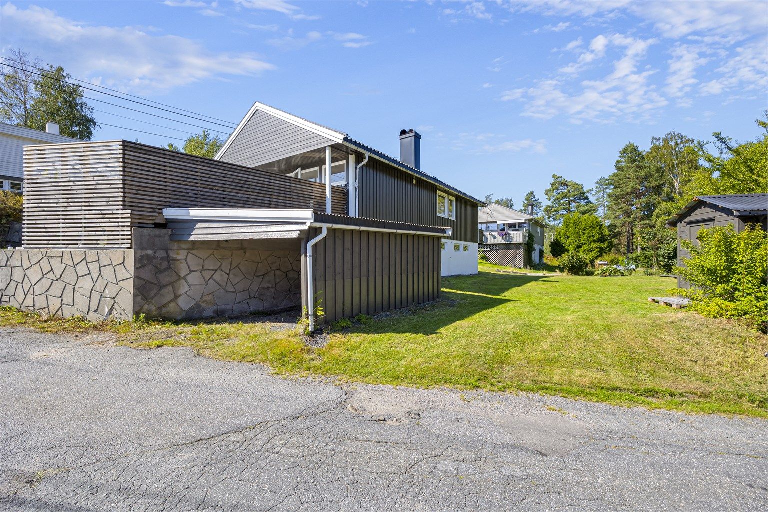 Carport og romslig plen på baksiden.