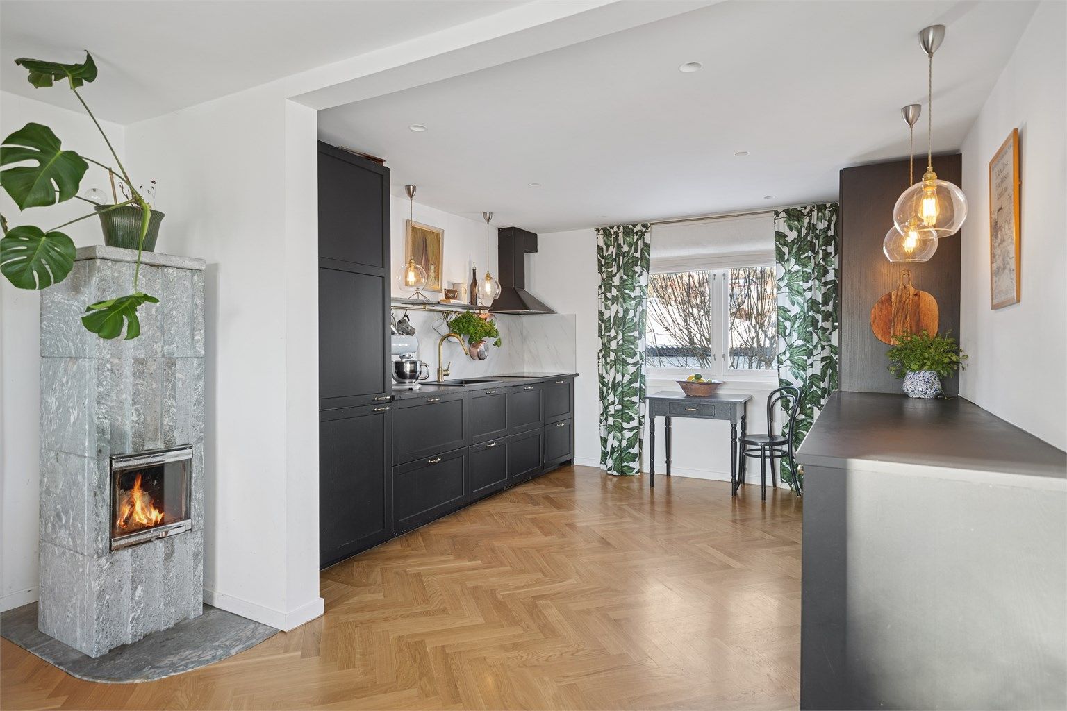 Åpent og sosialt kjøkken mot stuen, samt en vakker klebersteinsovn som både fungerer som romdeler og estetisk blikkfang.