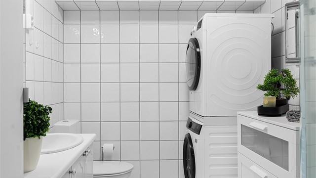 Dusjkabinett med dusjarmatur og gulvstående toalett. Opplegg for vaskemaskin.