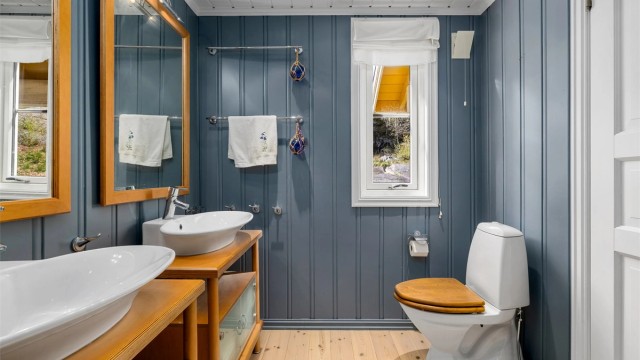 Lyst og romslig bad i 1. etasje med malte overflater og klassisk tregulv. Rommet er smakfullt innredet med to servanter med store speil, høyskap, og møblet er i solid heltre. Dusjkabinett og toalett er montert.