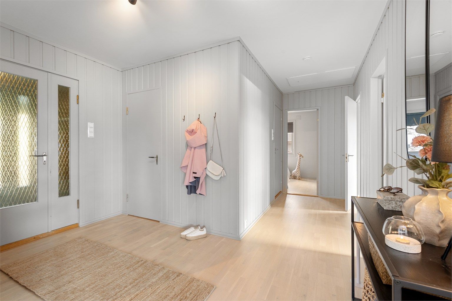 Inngangspartiet har flislagt gulv i vindfanget og leder inn til en lys og innbydende gang