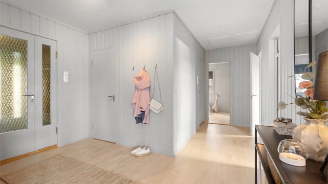 Inngangspartiet har flislagt gulv i vindfanget og leder inn til en lys og innbydende gang
