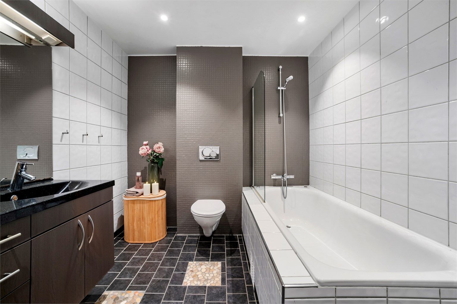 Badet i 1. etasje har flislagt gulv med gulvvarme, badekar og vegghengt toalett.