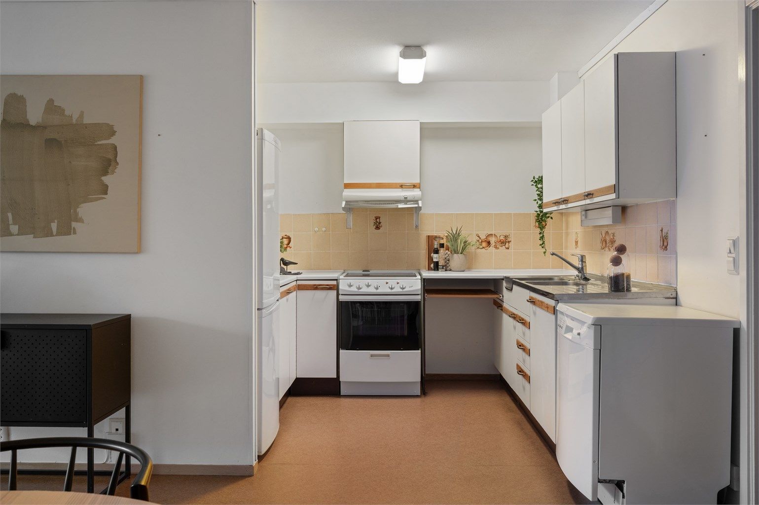 Kjøkkeninnredning med slette fronter og benkeplate i laminat med og vask med stålbeslag. Opplegg for frittstående oppvaskmaskin.