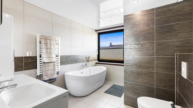 Badet er lekkert flislagt og utstyrt med dusjhørne, badekar, dobbel servantinnredning og vegghengt toalett.