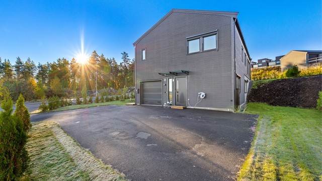 Asfaltert gårdsplass med god plass til biloppstilling foran inngangspartiet.
