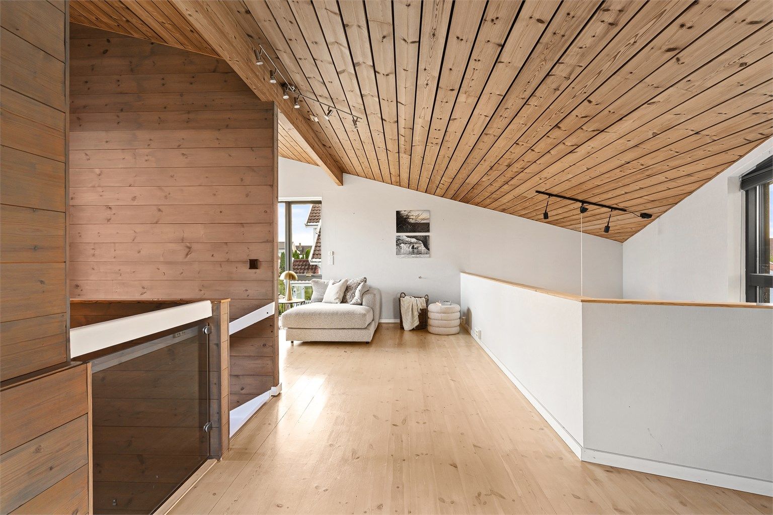 Loftstue i andre etasje med furugulv og skråhimling i tre.