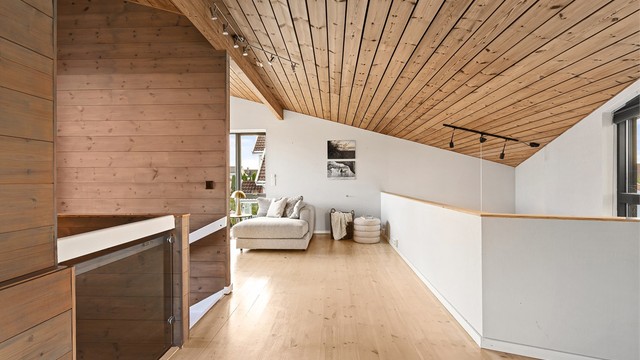 Loftstue i andre etasje med furugulv og skråhimling i tre.