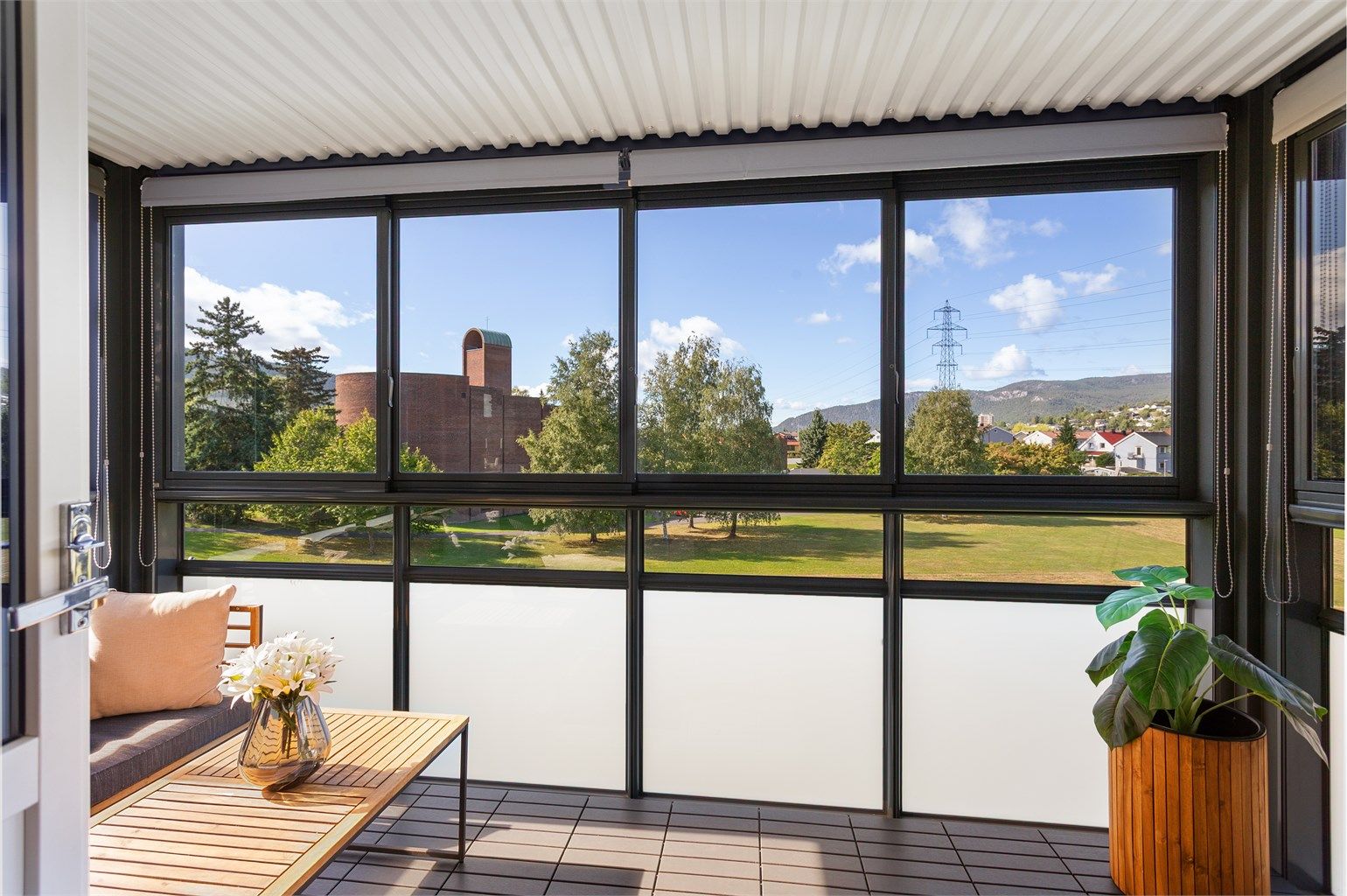 Fin innglassset balkong med skyvbare glassfelter - utsikt mot store plenarealer