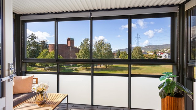 Fin innglassset balkong med skyvbare glassfelter - utsikt mot store plenarealer