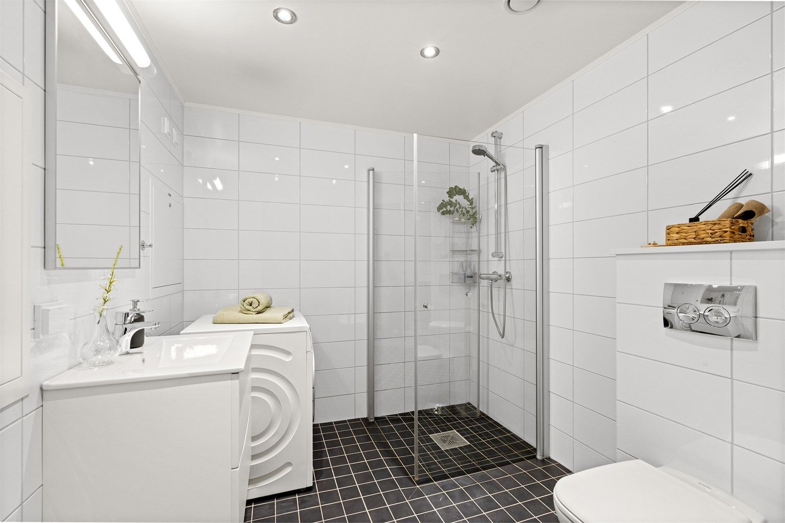 Dusj med innfellbare glassdører, speil med overlys og opplegg for vaskemaskin.