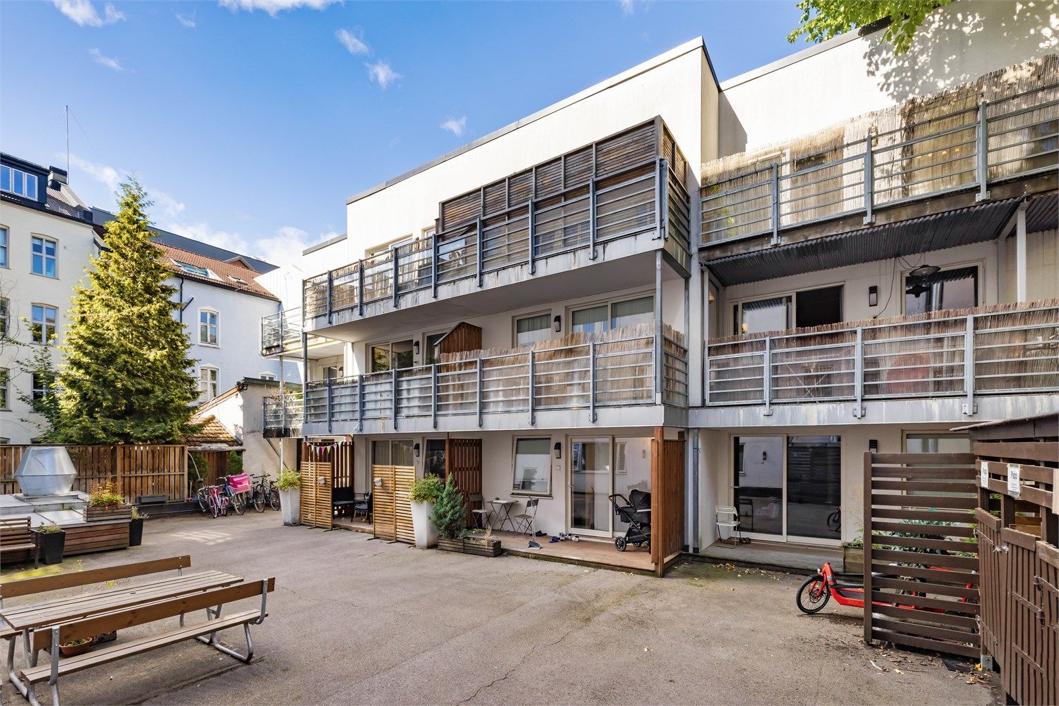 Pent opparbeidet bakgård med diverse beplantning og sittebenker.