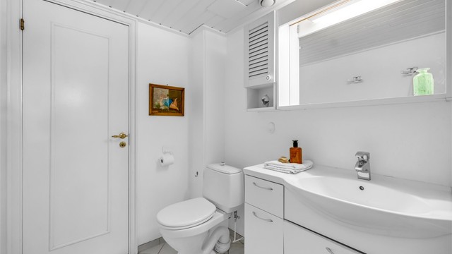 Badet er innredet med servantinnredning med heldekkende servant, speilskap med belysning og stikkontakt, gulvstående toalett samt frittstående badekar med dusjløsning.