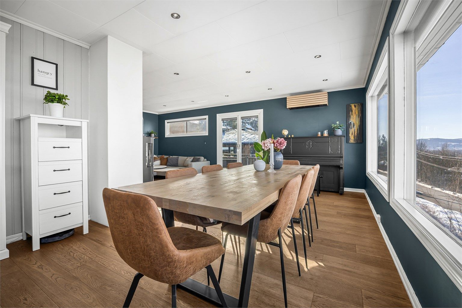 Gjennomgående parkettgulv binder sammen stue, spisestue og kjøkken på en helhetlig måte.