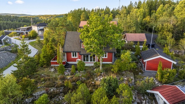 Boligen har en fin og tilbaketrukket tomt med gruset innkjøring og frodige omgivelser.
