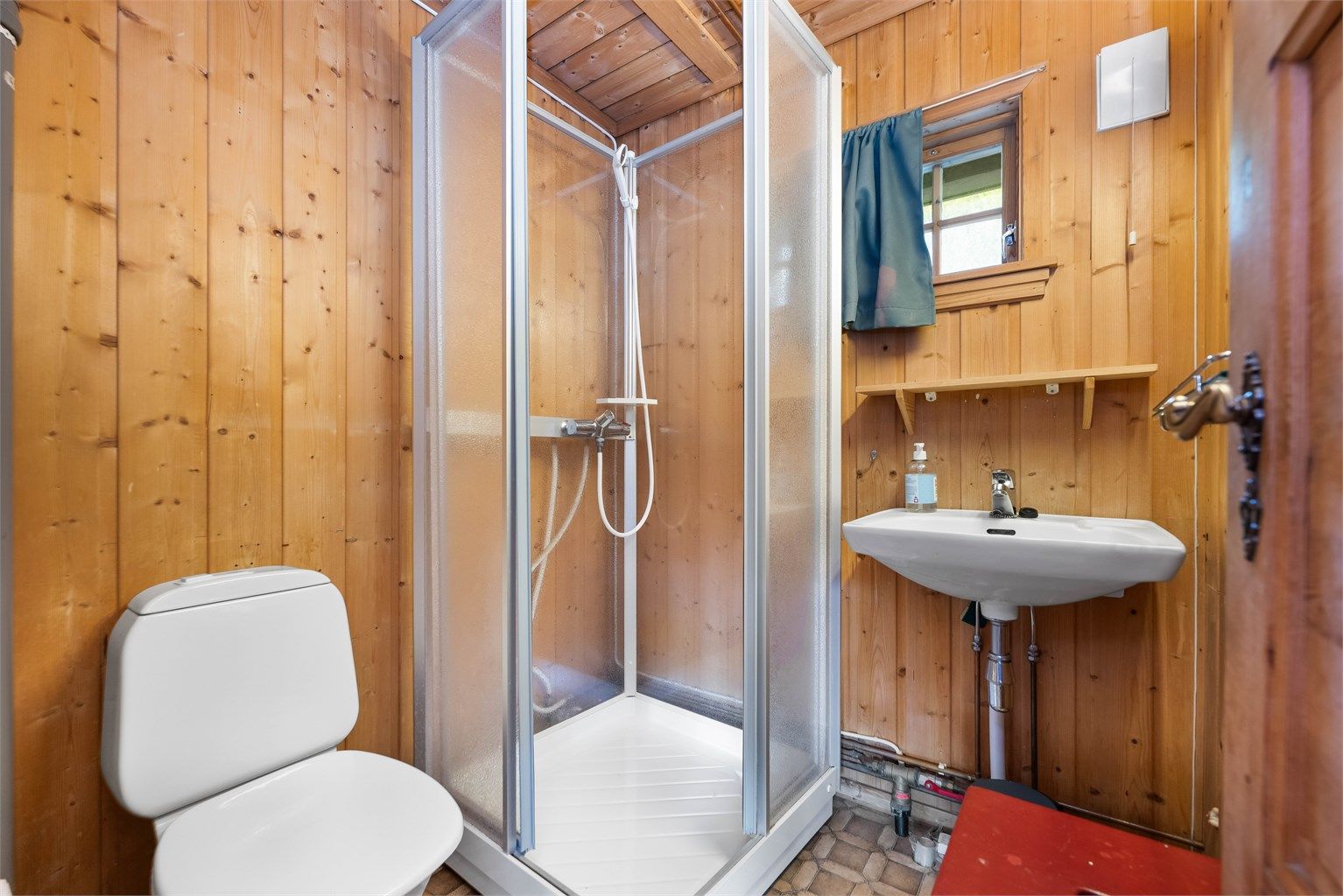 Badet er utstyrt med vegghengt servant og speil med overlys.