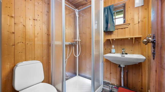 Badet er utstyrt med vegghengt servant og speil med overlys.