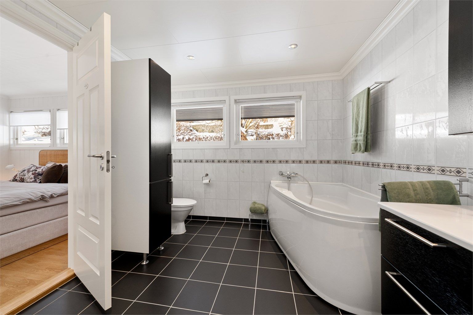 Badet i hovedetasjen har hjørnebadekar, dusjkabinett og gulvstående toalett