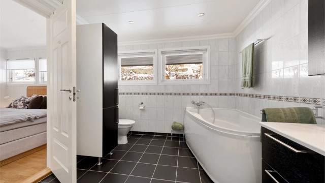 Badet i hovedetasjen har hjørnebadekar, dusjkabinett og gulvstående toalett