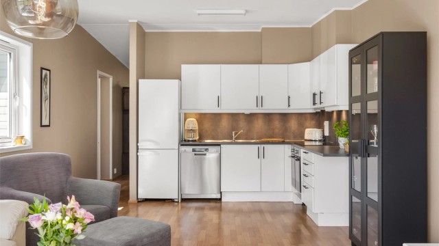 Stilrent kjøkken med integrert stekeovn og platetopp. Kjøkkenbenken er forlenget for å gi ekstra god arbeidsflate og bedre utnyttelse av sonen.
Foto: Borghagen Foto
