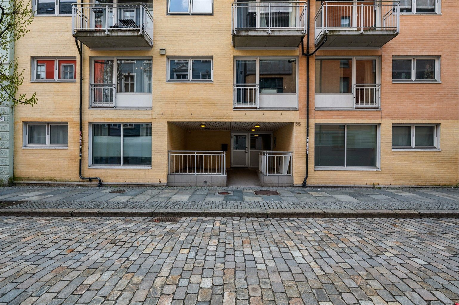 I en sjarmerende brosteinsbelagt gate ligger byggets inngang fint til med overbygget inngangsparti og heisen tar deg enkelt opp til leiligheten din.