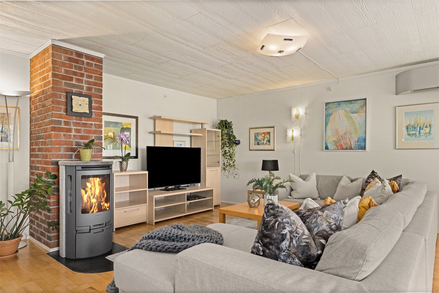 En teglsteinspipe gir karakter til rommet, og vedovnen bidrar med både varme og hygge.