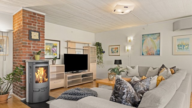 En teglsteinspipe gir karakter til rommet, og vedovnen bidrar med både varme og hygge.